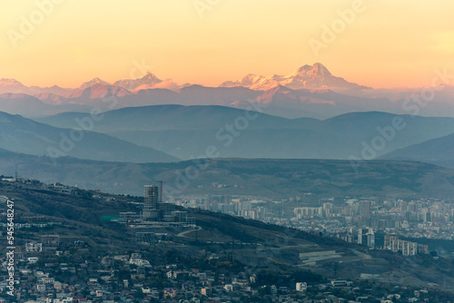 top view of tbilisi at dusk and mountain peaks on the horizon photo
