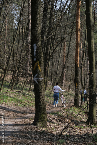 A portrait of girl walking with a bicycle in a Spring forest at Holosiivskyi National Nature Park, Kyiv, Ukraine