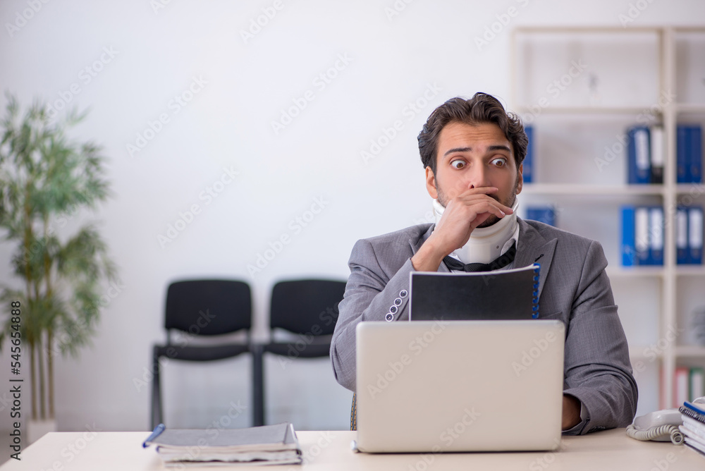 Young male employee after car accident working in the office Young male employee after car accident working in the office