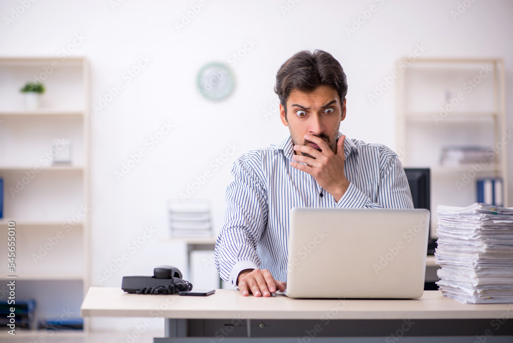 Young male employee and too much work in the office Young male employee and too much work in the office