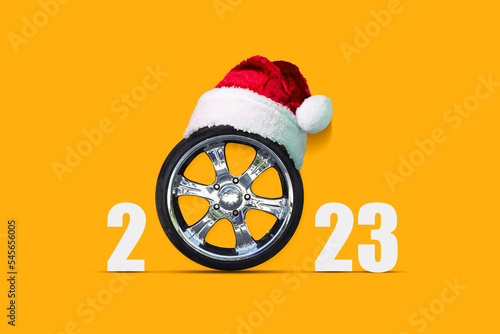 Car wheel in a Santa Hat on a bright orange background. Ccopy space. Place for text. New Year card. photo