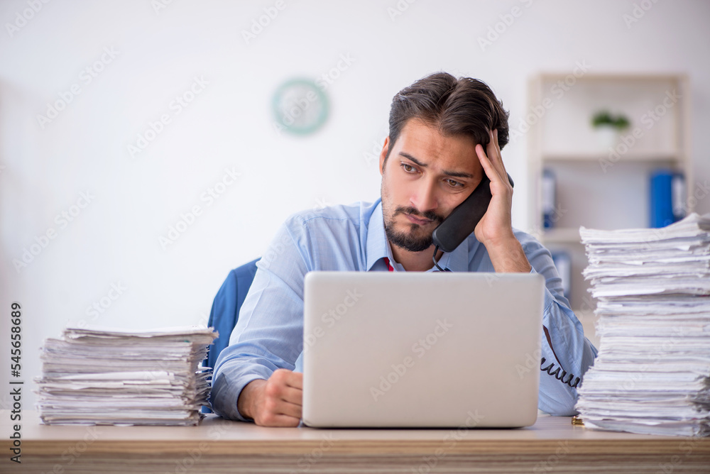 Young male employee and too much work in the office Young male employee and too much work in the office