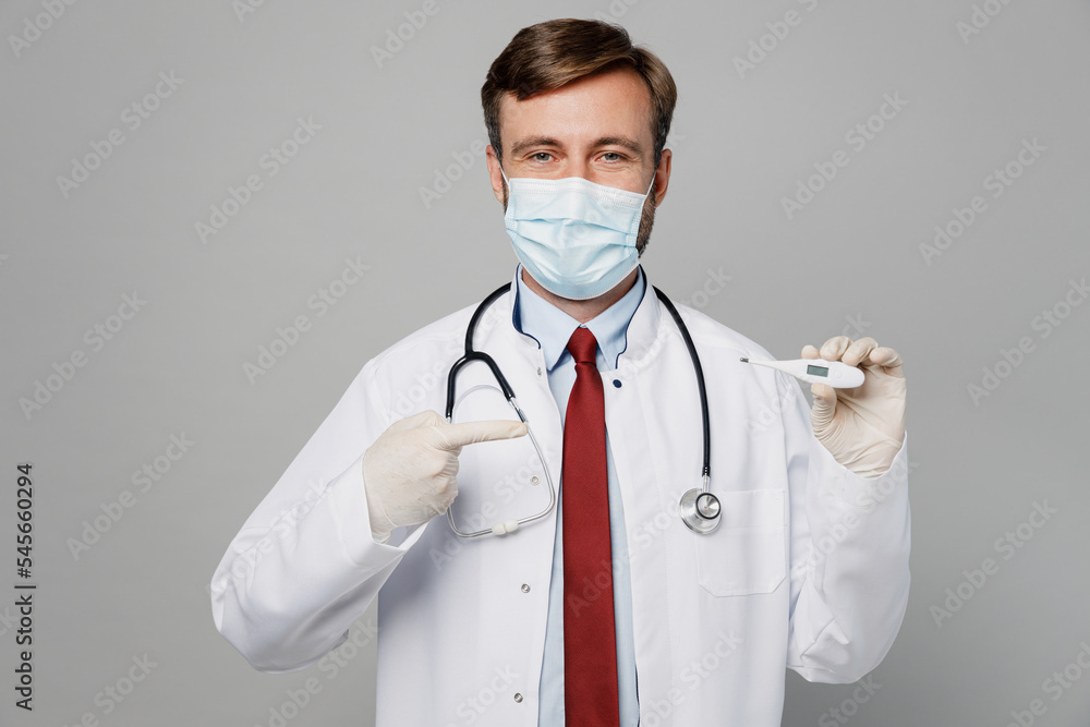 Male doctor man wear white medical gown suit mask gloves work in hospital hold in hand thermometer show temperature isolated on plain grey color background studio portrait Healthcare medicine concept Male doctor man wear white medical gown suit mask gloves work in hospital hold in hand thermometer show temperature isolated on plain grey color background studio portrait Healthcare medicine concept