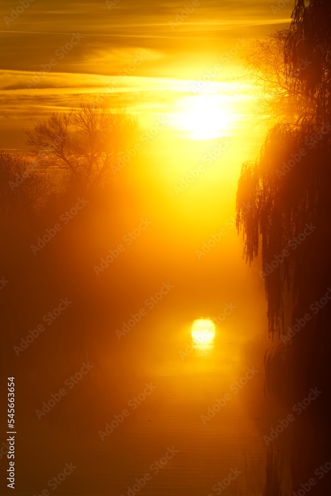 Reflection of the Rising Sun in a River Covered in Fog