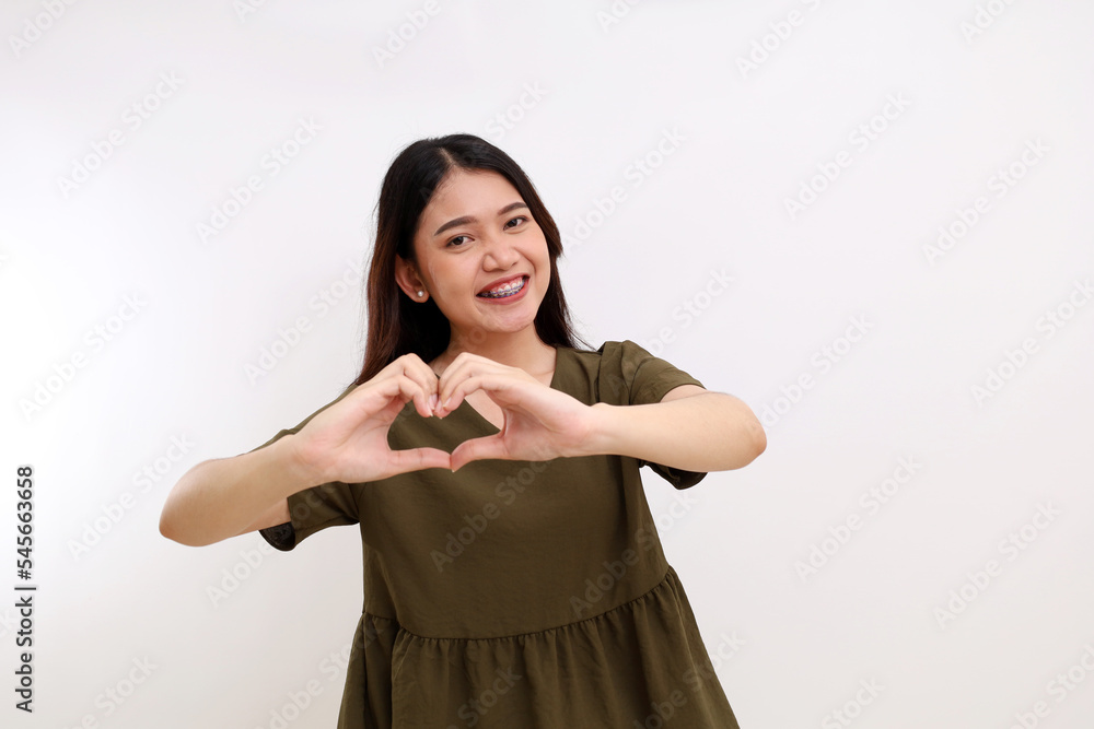 Portrait of beautiful young asian woman standing while smiling and showing love shape hand gesture. Portrait of beautiful young asian woman standing while smiling and showing love shape hand gesture.