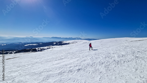 Woman hiking in snow covered landscape near Ladinger Spitz, Saualpe, Lavanttal Alps, Carinthia, Austria, Europe. Trekking in Austrian Alps in winter on a sunny day. Ski touring and snow shoe tourism