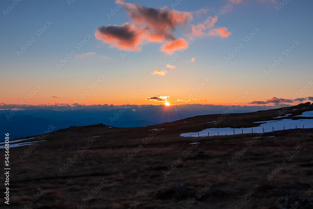 Scenic view on alpine pasture during sunset from mountain peak Zingerle Kreuz, Saualpe, Lavanttal Alps, Carinthia, Austria, Europe. Hiking trail Wolfsberg. Warm red colored clouds creating calm vibes