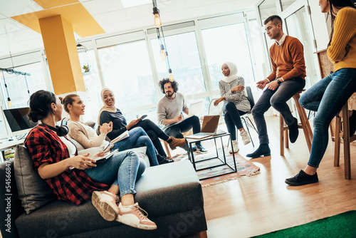 Young designer giving some new ideas about project to his partners in conference room. Business people discussing over new business project in office.