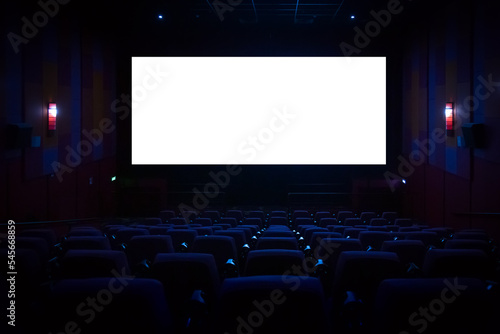 Empty cinema auditorium with empty white screen. Empty rows of theater or movie seats.