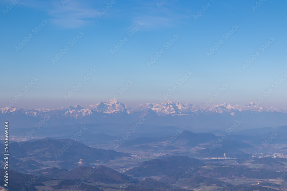 Scenic view of Karawanks (Karawanken) mountain range at early morning after sunrise seen from Saualpe, Lavanttal Alps, Carinthia, Austria, Europe. Snowcapped mountain peaks in Southern Limestone Alps