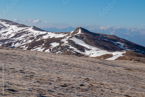 Woman hiking on frozen alpine meadow from Ladinger Spitz to Gertrusk, Saualpe, Lavanttal Alps, Carinthia, Austria, Europe. Morning hoar frost on cold early spring day. Trekking in the Austrian Alps photo