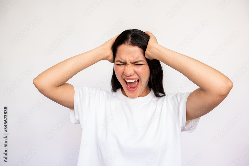 Portrait of despaired young woman holding head in hands over white background. Caucasian lady wearing white T-shirt crying and screaming in stress. Frustration concept Portrait of despaired young woman holding head in hands over white background. Caucasian lady wearing white T-shirt crying and screaming in stress. Frustration concept