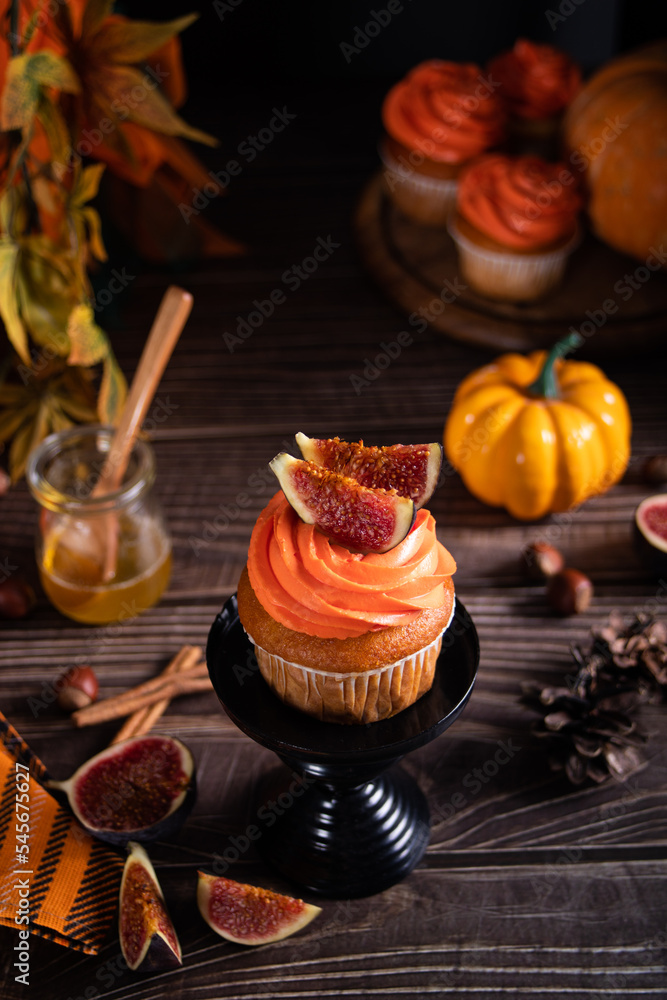 Delicious homemade autumn season spicy pumpkin cupcakes with whipped orange cream with fruit figs.