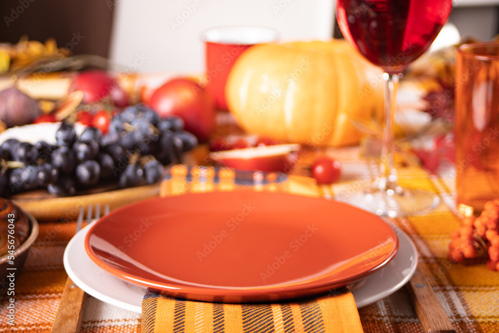 Naklejka premium Autumn place setting dinner for celebration Thanksgiving Day. Holiday party. Festive table. Snacks, friuts,pie, pumpkin, vegetables, wine glasses.