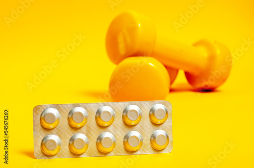 silver plate with pills on a background of yellow dumbbells.