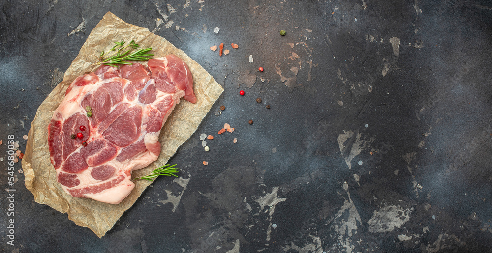 pork meat steaks with rosemary and pepper on a dark background. Long banner format. top view