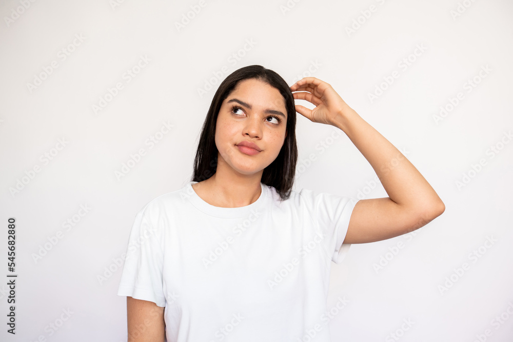 Portrait of thoughtful young woman scratching head over white background. Caucasian lady wearing white T-shirt looking away with pensive expression. Planning or dreaming concept Portrait of thoughtful young woman scratching head over white background. Caucasian lady wearing white T-shirt looking away with pensive expression. Planning or dreaming concept