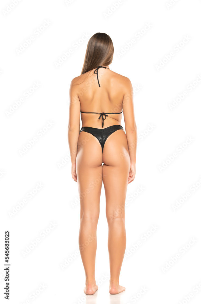 Beautiful young woman in black bikini on a white background. Back view Beautiful young woman in black bikini on a white background. Back view