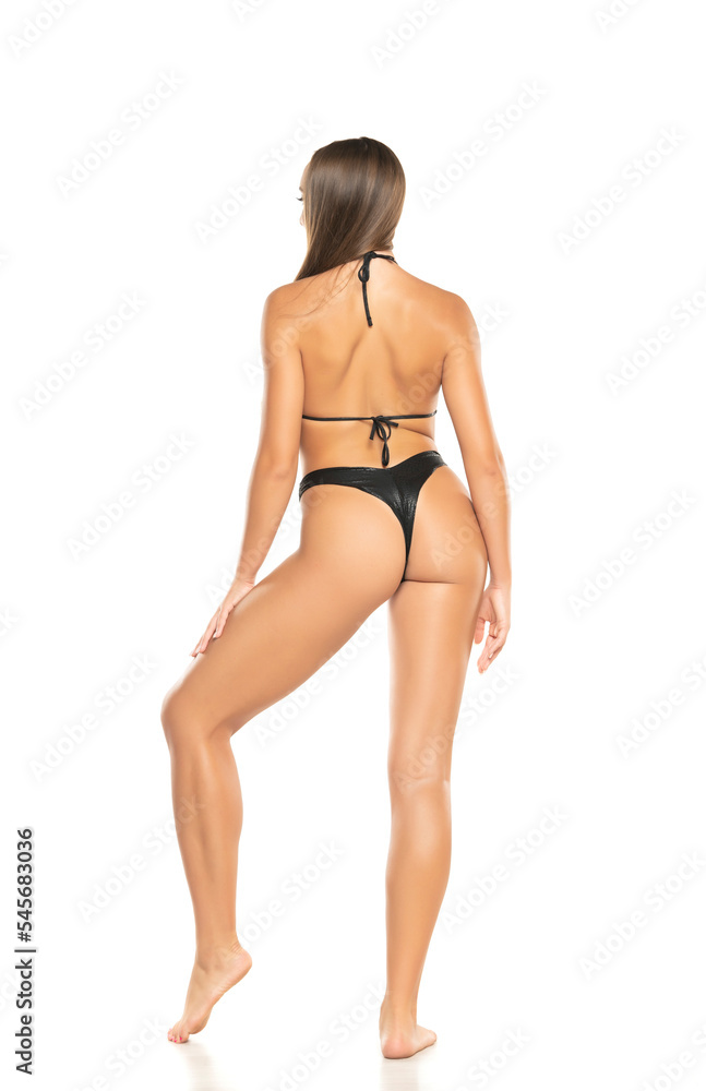 Beautiful young woman in black bikini on a white background. Back view Beautiful young woman in black bikini on a white background. Back view