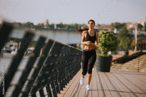 Active young beautiful woman running on the promenade along the riverside © BGStock72