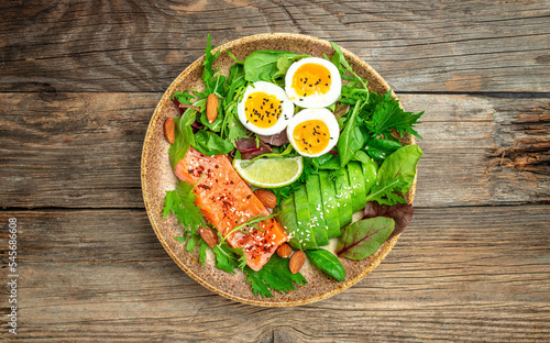Salmon fillet with fresh salad, grape, eggs and avocado on a wooden background. set of healthy food for keto diet. Top view