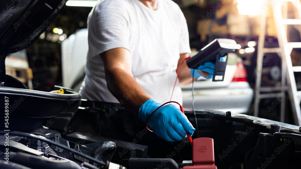 Senior mechanic man uses multimeter voltmeter to check voltage level in car battery at car service and maintenance garage. Senior mechanic man uses multimeter voltmeter to check voltage level in car battery at car service and maintenance garage.