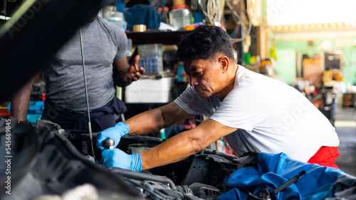 senior asian male mechanic engineering working on Vehicle in Car Service. Repair specialist, technical maintenance. Small business owner.