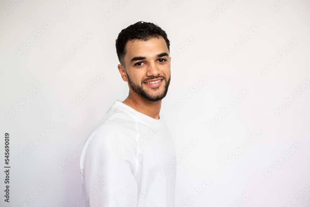 Portrait of happy young man looking at camera and smiling. Bearded man wearing white T-shirt posing over white background. Male beauty concept Portrait of happy young man looking at camera and smiling. Bearded man wearing white T-shirt posing over white background. Male beauty concept