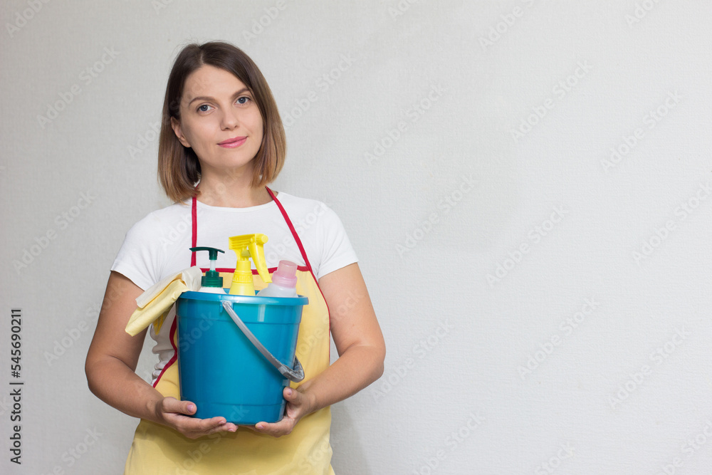 The girl holds a bucket and cleaning products in her hands The girl holds a bucket and cleaning products in her hands