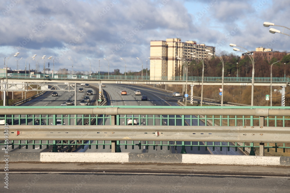 Curbstone and railing of the bridge over a highway on the background of a busy highway, traffic, urbanism