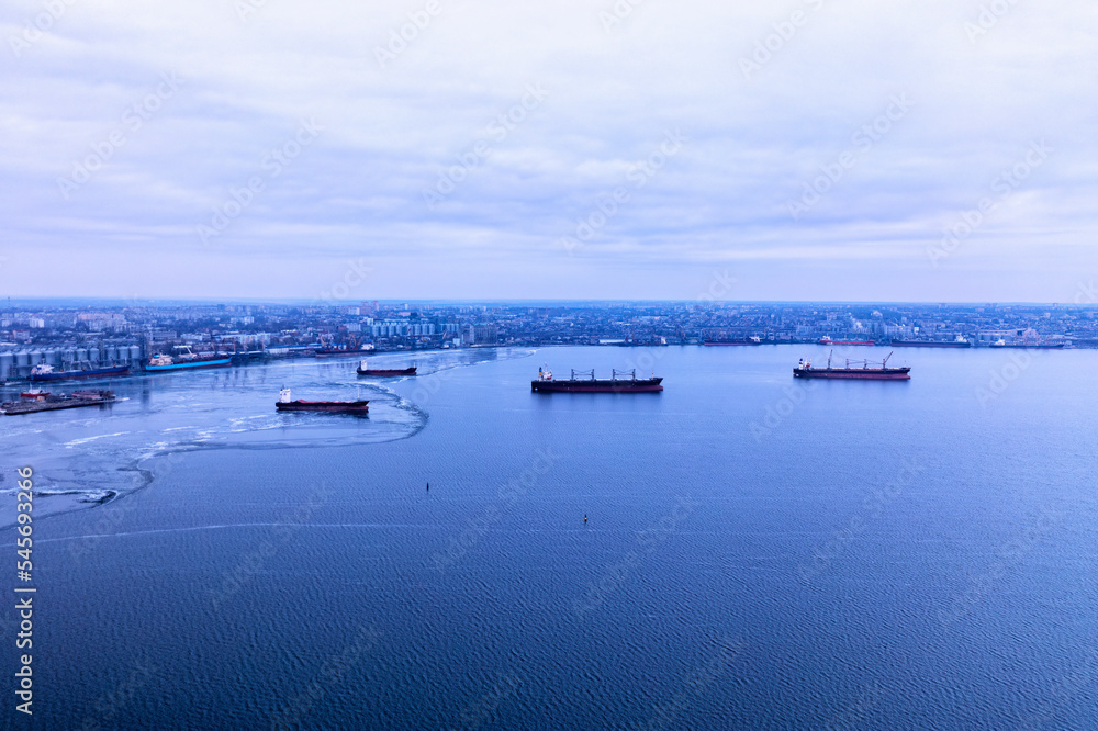 A cargo ships standing on a frozen river. Freight transportation concept, import export and business logistics, aerial view in winter. Nikolaev, Ukraine A cargo ships standing on a frozen river. Freight transportation concept, import export and business logistics, aerial view in winter. Nikolaev, Ukraine