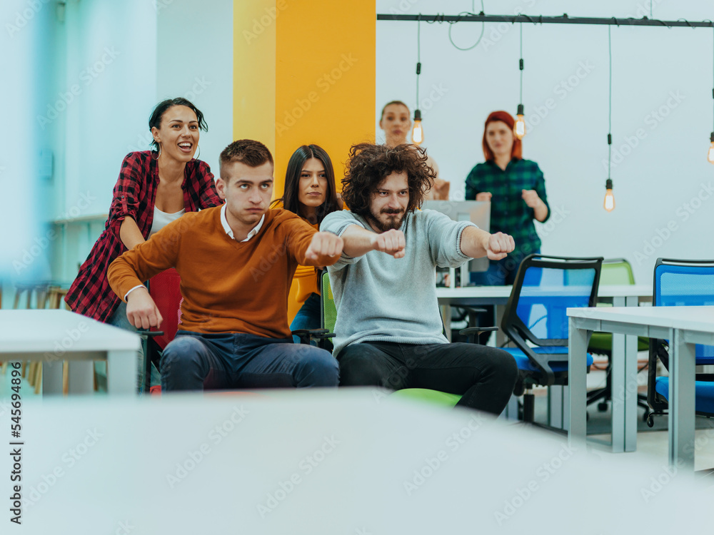 Team building and office fun. Young cheerful businesspeople in smart casual wear having fun while racing on office chairs and smiling. Team building and office fun. Young cheerful businesspeople in smart casual wear having fun while racing on office chairs and smiling.