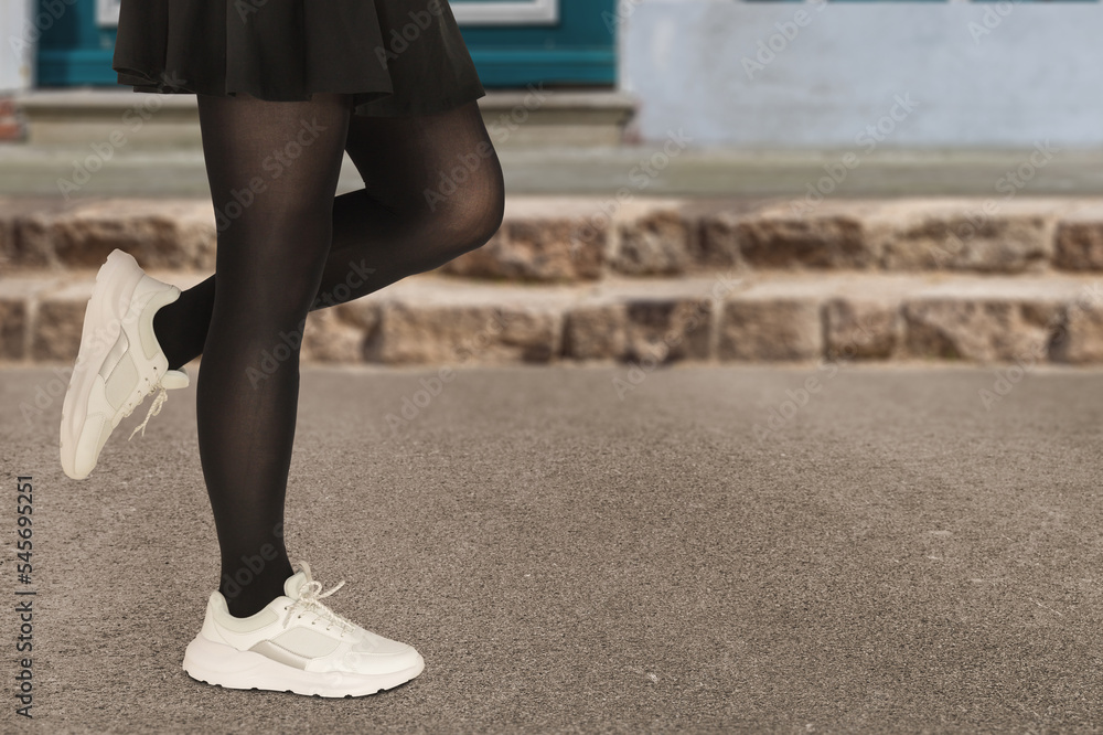 Close-up woman in stylish white sneakers in a black skirt with pantyhose.  Fashionable autumn or spring concept. Stock-Foto | Adobe Stock