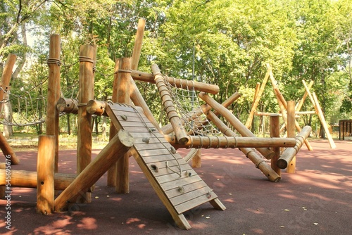 Fototapeta Naklejka Na Ścianę i Meble -  Wooden modern ecological safety children outdoor playground equipment in public park. Nature architecture construction playhouse in city. Children rest and childhood concept. Idea for games on air.