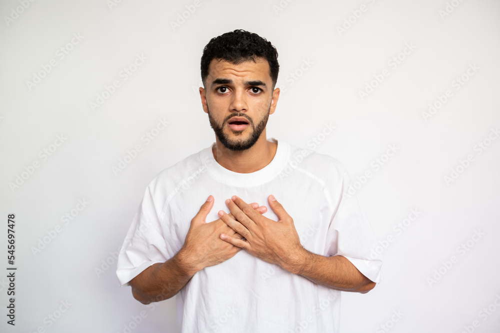 Portrait of indignant young man making excuses. Latin American guy wearing white T-shirt looking at camera in stress over white background. Apology concept Portrait of indignant young man making excuses. Latin American guy wearing white T-shirt looking at camera in stress over white background. Apology concept