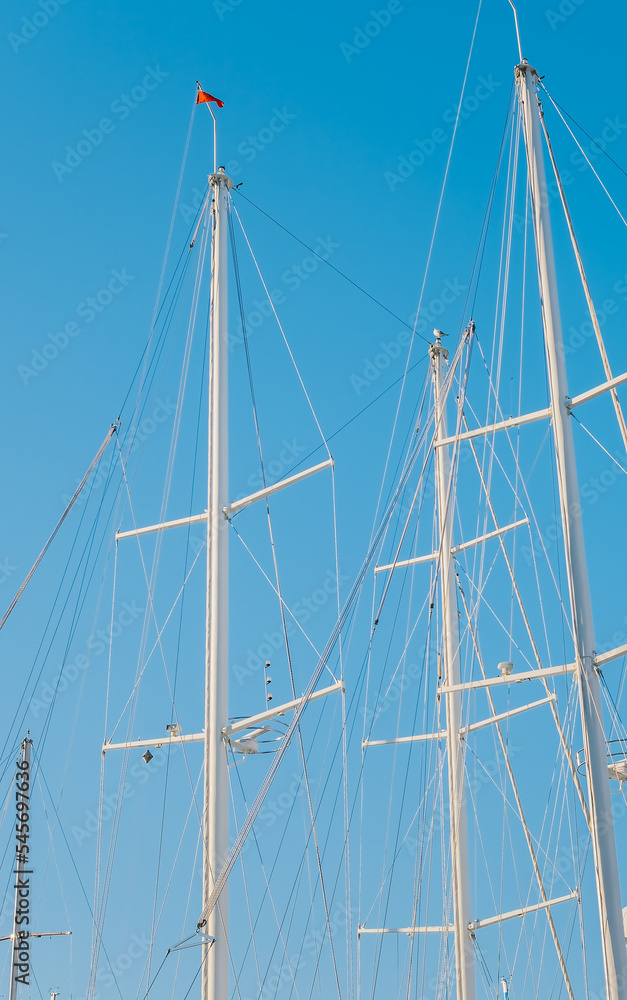 Silhouettes of match yachts in the marina against the backdrop of a clear blue sky, vertical frame, idea for a background or news about yachting Silhouettes of match yachts in the marina against the backdrop of a clear blue sky, vertical frame, idea for a background or news about yachting