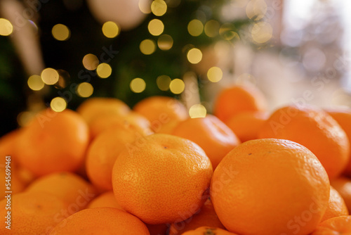 Christmas composition on colorful bokeh background. Mandarins against a background of blurry defocused lights. Concept for Christmas, New Year