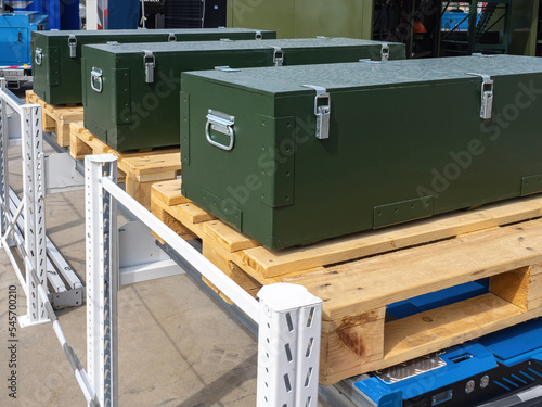 Boxes with industrial equipment. Oblong green boxes on wooden pallets. Boxes for transporting industrial equipment. Rack with protective containers. Wooden containers for industrial machines