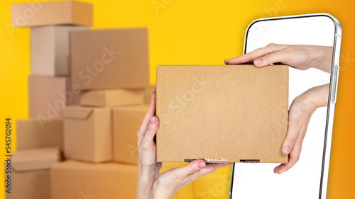 Process of delivering goods. Box in hand. Box in screen of mobile phone. Concept ordering delivery through application. Mobile application courier company. Hands with box in smartphone. Art blurred © Grispb