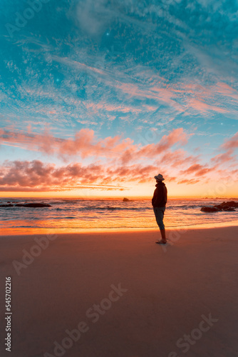 silhouette of a person on the beach contemplating a beautiful sunset on the horizon over the pacific ocean