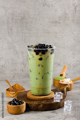 Boba or tapioca pearls is taiwan bubble milk tea in plastic cup with matcha flavor on texture  background, summers refreshment.