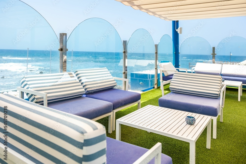 Fototapeta premium Cafe tables and chairs with blue and white strips with a great view of the sea