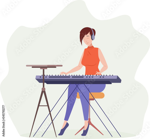 Young woman musician in headphones playing synthesizer at recording studio
