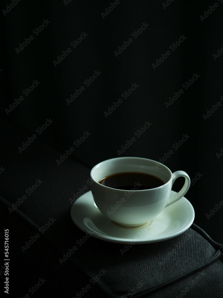 Vertical high angle shot of a white instant coffee mug on a black couch Vertical high angle shot of a white instant coffee mug on a black couch