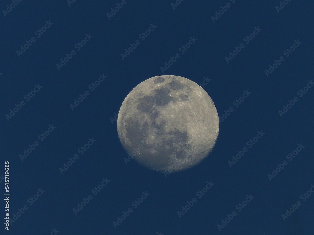 Beautiful shot of the full moon at dusk with a dark blue sky background Beautiful shot of the full moon at dusk with a dark blue sky background