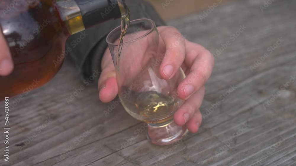 Man pouring alcohol from bottle into glass