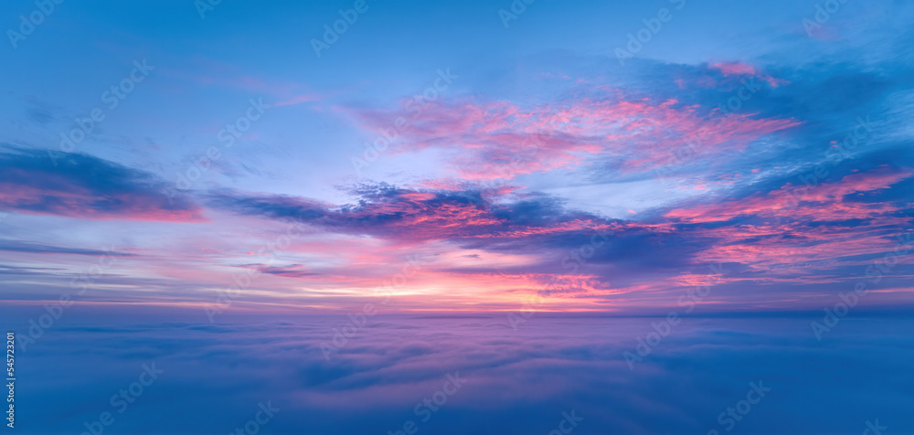 Panoramic, aerial view of sky between two layers of clouds in pink, blue and violet colors.  After sunset sky.