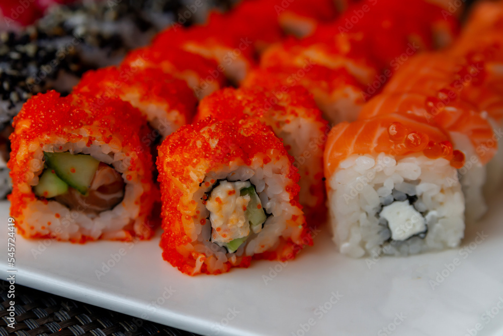 a large set of sushi with rice, Asian cuisine, various sushi rolls served on a white square ceramic plate, wooden chopsticks a large set of sushi with rice, Asian cuisine, various sushi rolls served on a white square ceramic plate, wooden chopsticks
