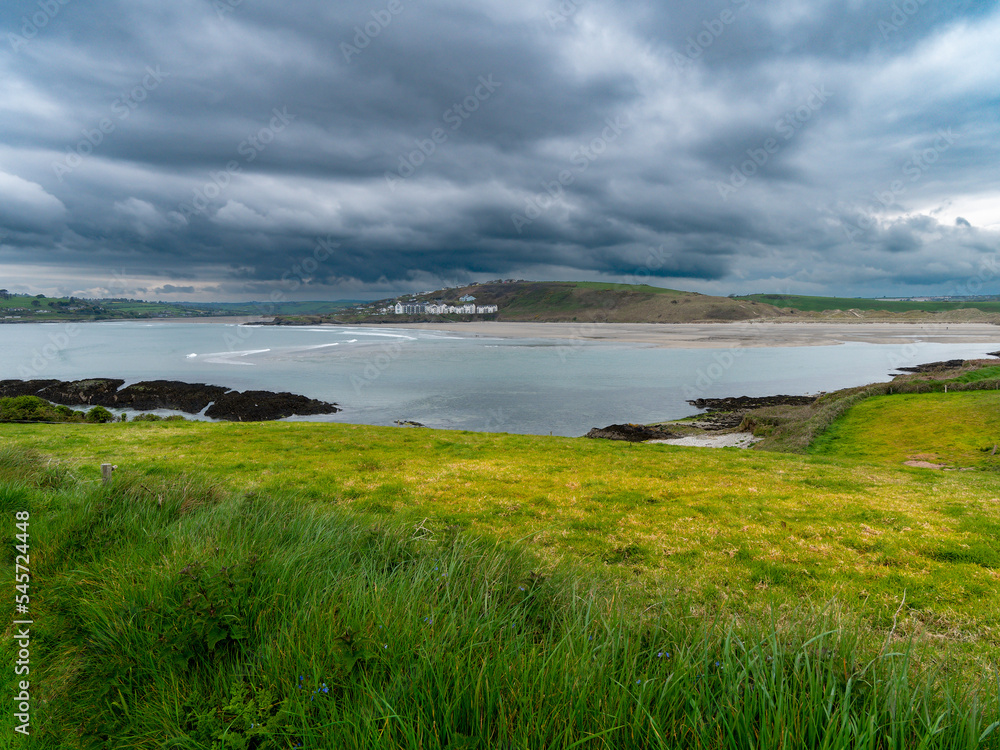 View of Clonakilty Bay. Thick grass near the sea. The coastline of the south of Ireland. Seaside landscape. Cloudy weather before a thunderstorm. View of Clonakilty Bay. Thick grass near the sea. The coastline of the south of Ireland. Seaside landscape. Cloudy weather before a thunderstorm.