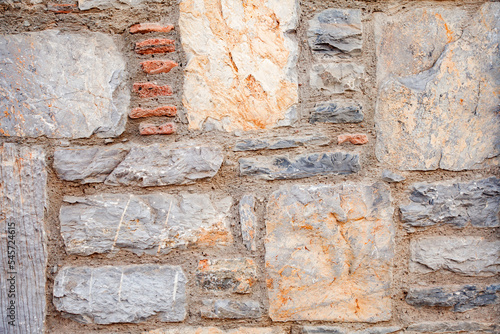 Wall from bricks, rectangular and square stones, texture of brown, yellow and red stone background texture.